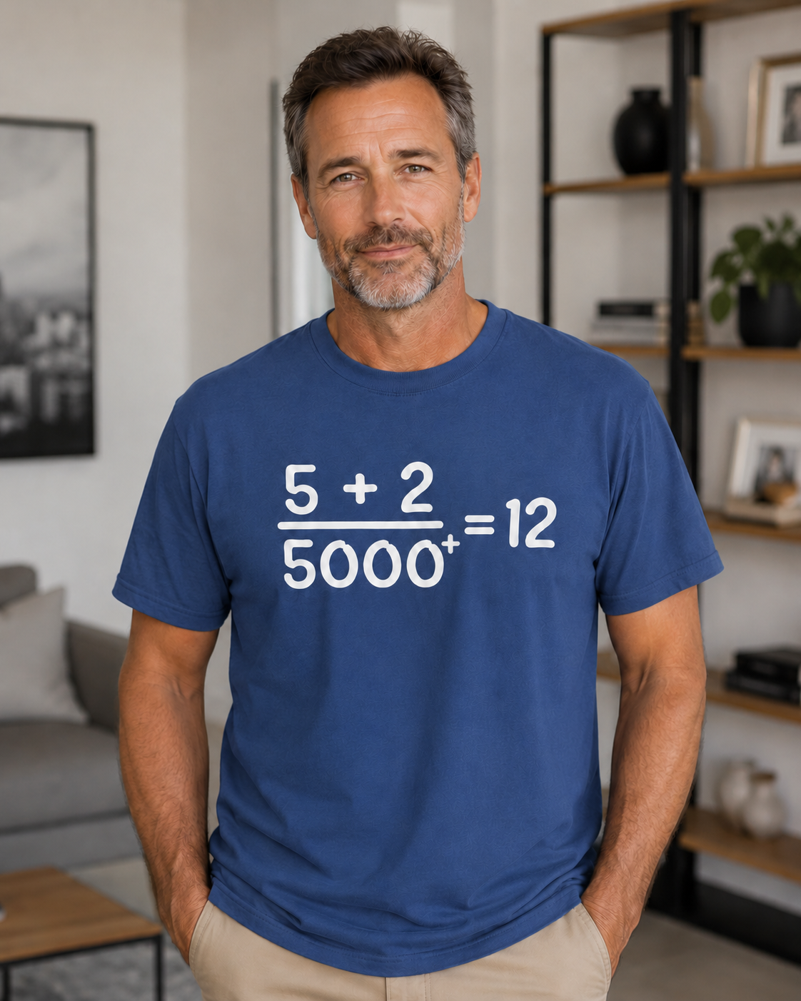 Older clean-cut man wearing a china blue Comfort Colors Christian math graphic t-shirt indoors in a modern home setting featuring the “5 + 2 / 5000+ = 12” design.