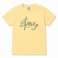 Youth Christian t-shirt in butter yellow featuring “She is Strong” with Proverbs 31:25 in black script lettering.