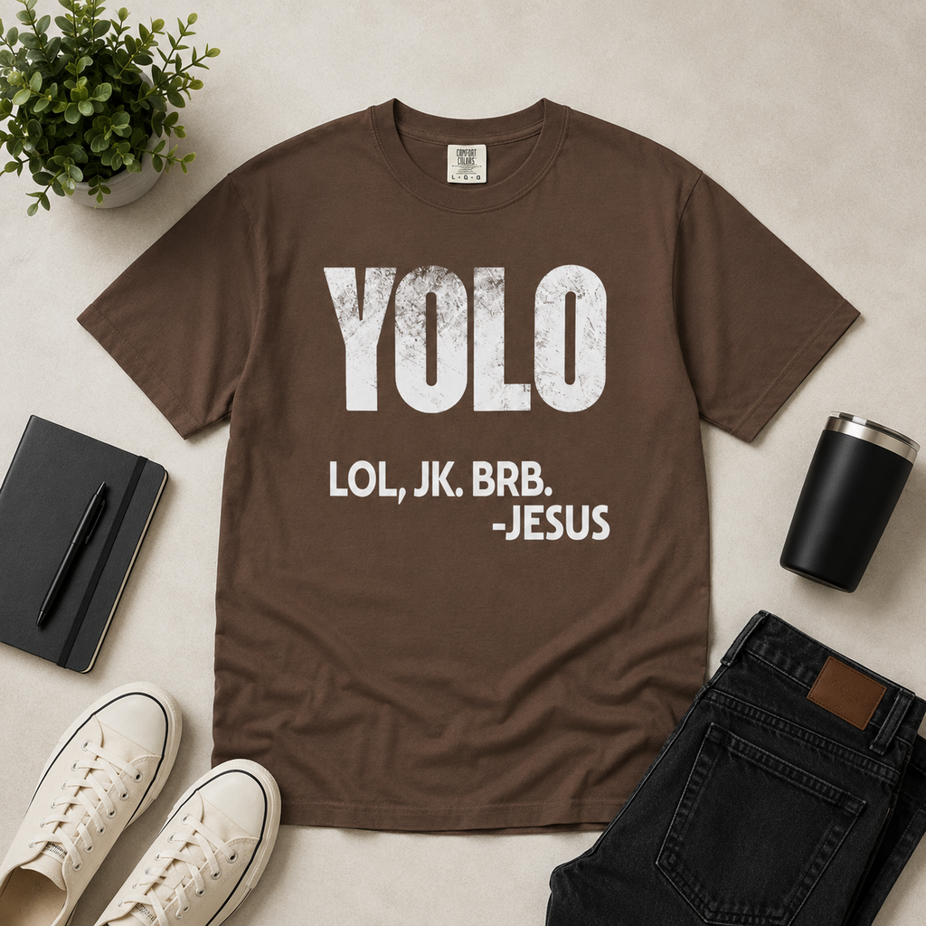 Espresso brown Christian humor t-shirt flat lay with distressed “YOLO LOL, JK. BRB. -Jesus” graphic styled with modern neutral accessories on a light beige background