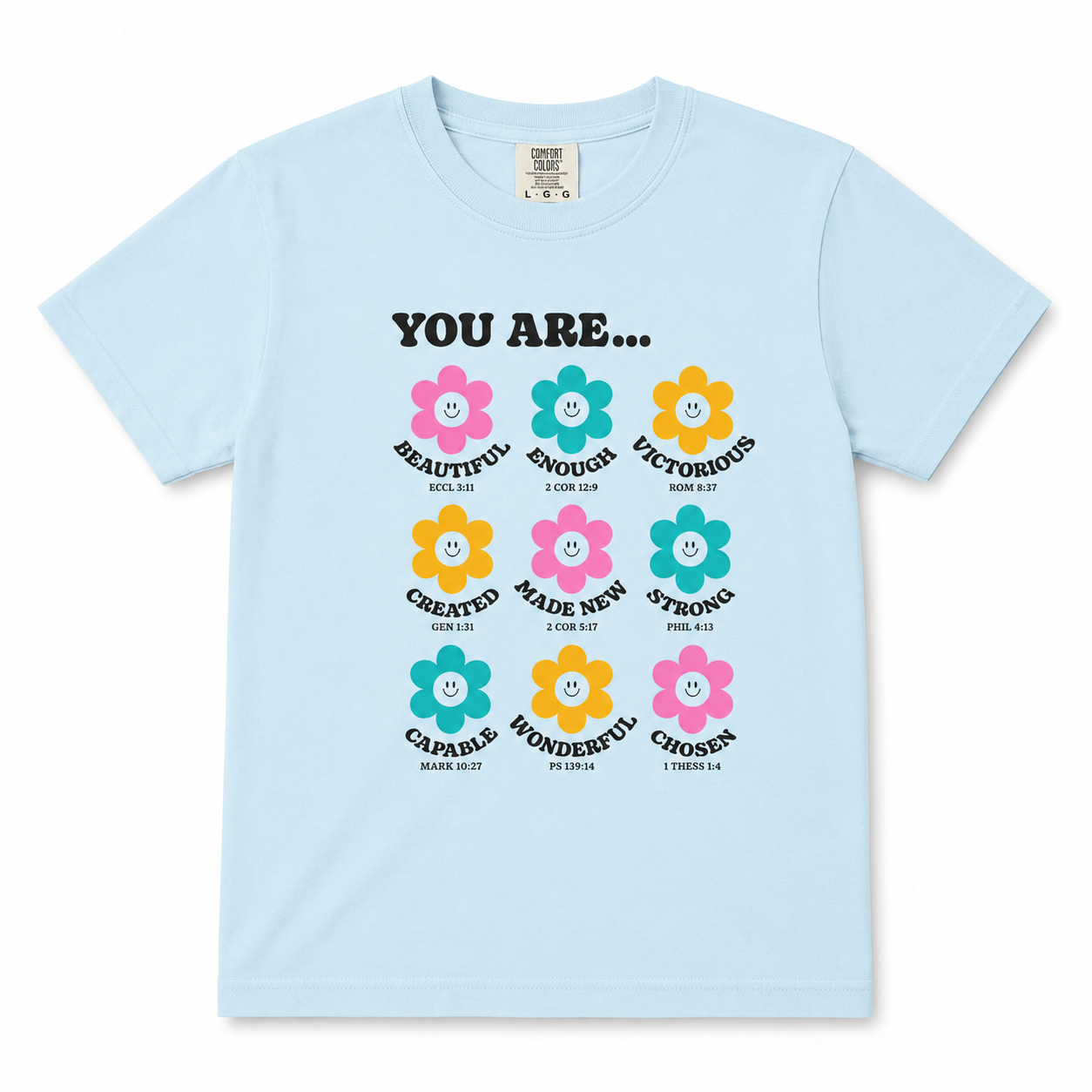 Clean product mockup of the chambray blue “You Are…” youth Christian t-shirt with colorful flower illustrations and faith-inspired positive messages on a neutral background.