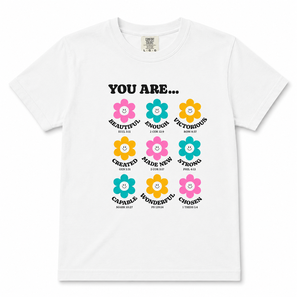 Clean product mockup of the white “You Are…” youth Christian t-shirt featuring colorful flower graphics and uplifting scripture-inspired affirmations on a neutral background.