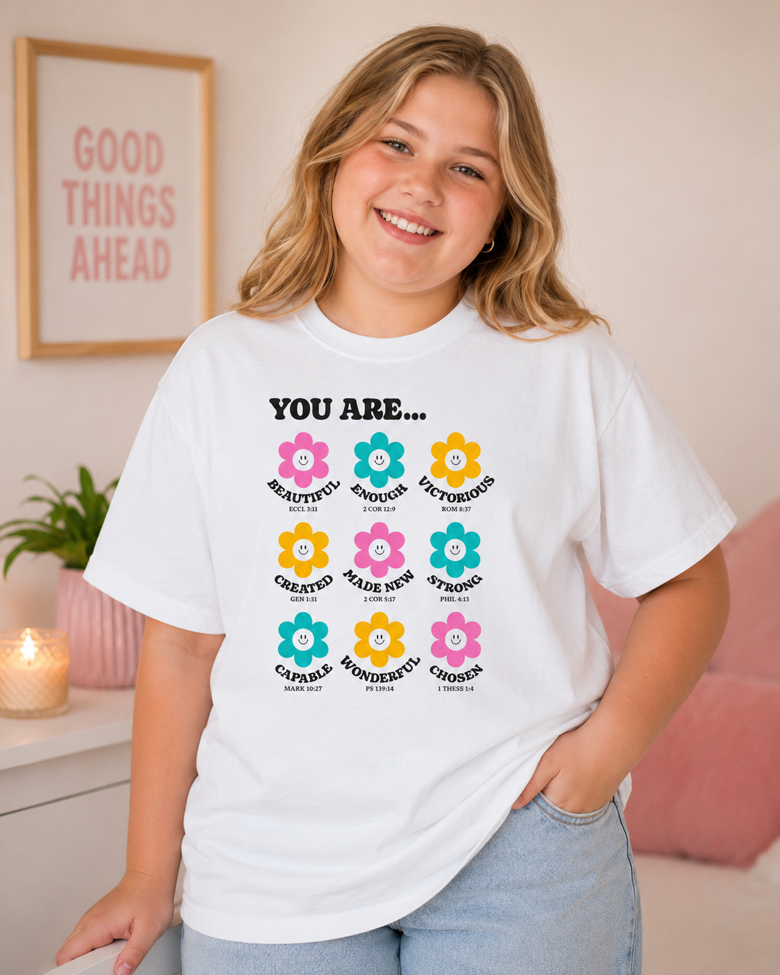 Plus size tween girl with blonde hair wearing a white “You Are…” Christian youth graphic t-shirt in a modern softly styled bedroom with a bright fun youthful aesthetic.